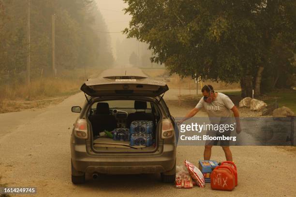 Resident collects supplies after a supply drop during a wildfire in the evacuated town of Scotch Creek, British Columbia, Canada, on Sunday, Aug. 20,...