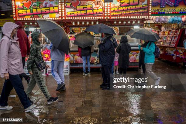 Holidaymakers brave the rain on Blackpool promenade on August 14, 2023 in Blackpool, England. A yellow weather warning is in place today amid a...