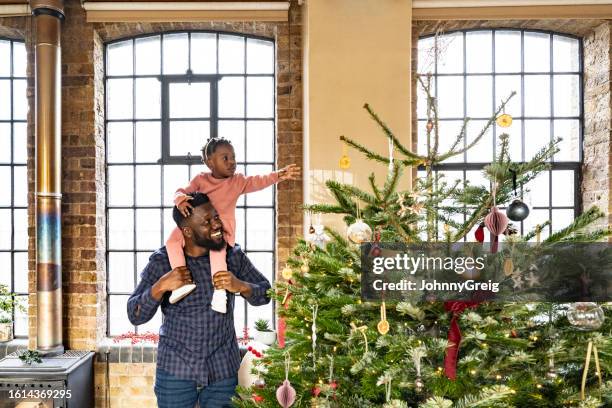 british father and toddler daughter looking at holiday tree - annual event stock pictures, royalty-free photos & images