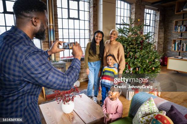 father photographing family in front of christmas tree - annual event stock pictures, royalty-free photos & images