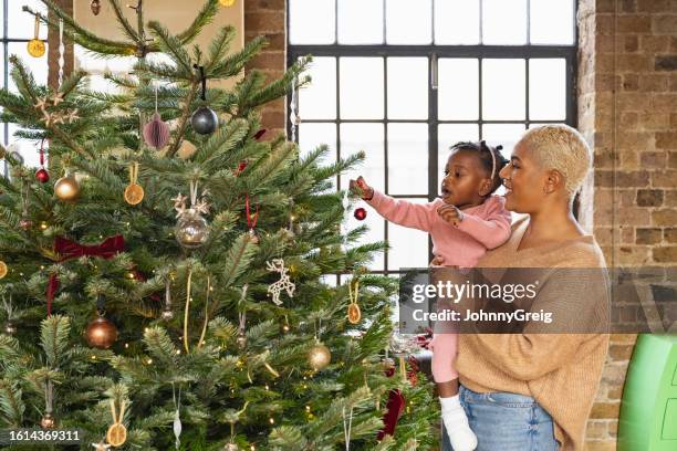 mother and toddler daughter decorating the christmas tree - pinaceae stock pictures, royalty-free photos & images