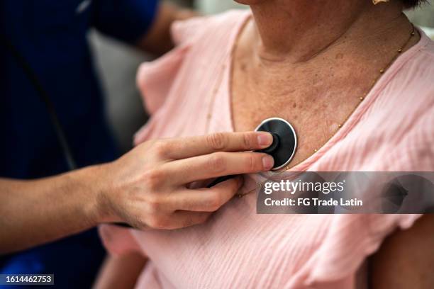 primo piano del medico che ascolta il battito cardiaco di una donna anziana - sentire il battito del cuore foto e immagini stock