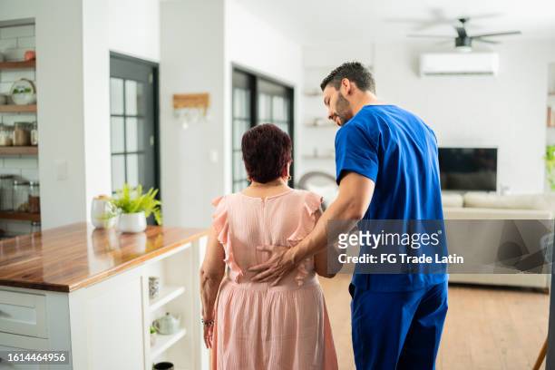 home caregiver helping senior woman to walk at house - home recovery stock pictures, royalty-free photos & images