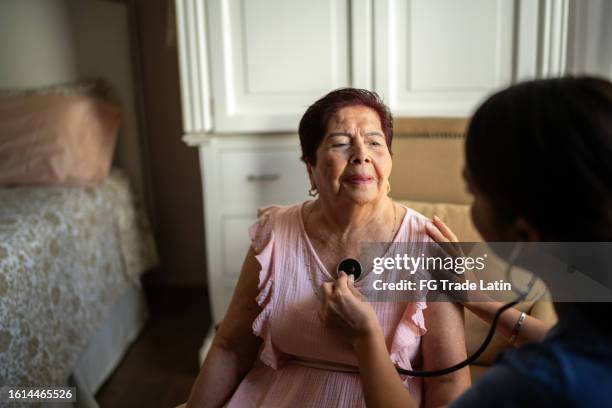aidante à domicile à l’écoute des battements de cœur d’une femme âgée dans une maison de soins infirmiers - auscultation-au-stéthoscope photos et images de collection