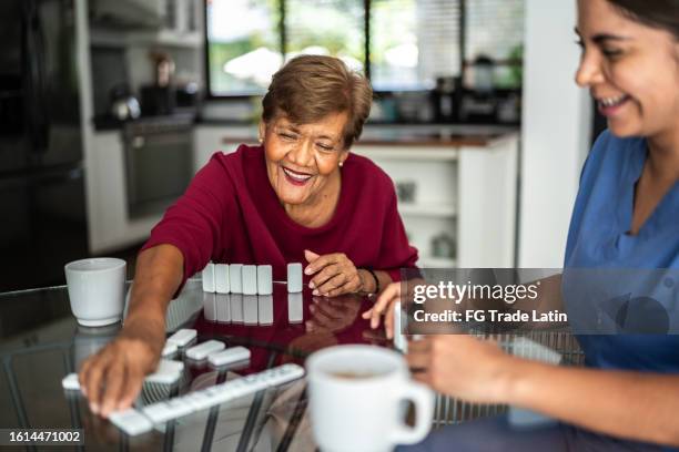 home caregiver playing domino with senior woman at a nursing home - dominos game stock pictures, royalty-free photos & images