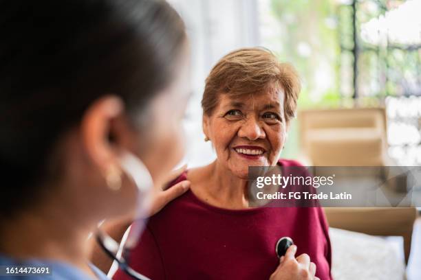 home caregiver listening to a senior woman's heartbeat in a nursing home - listening to heartbeat 個照片及圖片檔