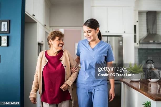 home caregiver helping senior woman to walk at house - 老人醫學 個照片及圖片檔