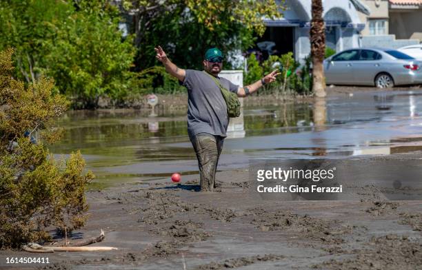 Isaac Lemus of Los Angeles tries to keep his balance walking though muddy flood waters on Avenida La Vista where his vehicle got stuck in the mud...