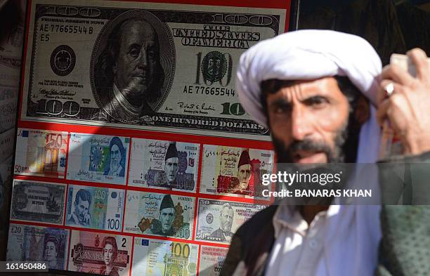 Pakistani pedestrian walks past the currency exchange shop in Quetta on February 11, 2013. The Pakistani rupee on Monday sank to an all-time low...