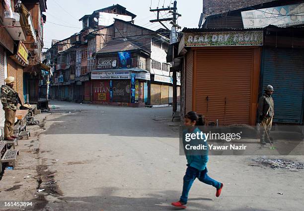Young Kashmiri Muslim girl dashes across a road Indian paramilitary soldiers stand guard during a curfew on the third consecutive day, following the...