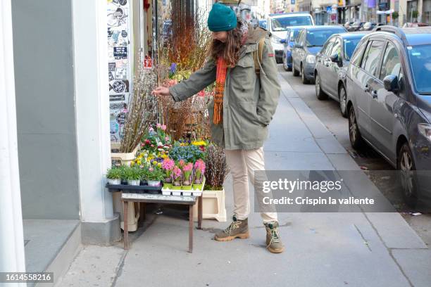 woman browsing in a small flower shop on a street in the wintertime - reusable shopping bag drawing stock-fotos und bilder