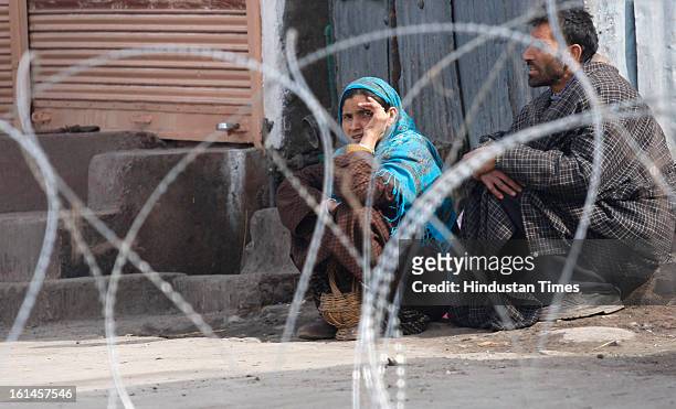 Couple waiting for the police to cross the road blocked by barbed wire on the 3rd day of curfew on February 11, 2013 in Srinagar, India. Kashmir...