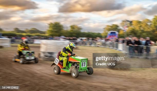 Two racing lawn mower drivers jostle for position at dusk in the BLMRA 500, a Le Mans style 500 mile overnight lawn mower race in a field in West...