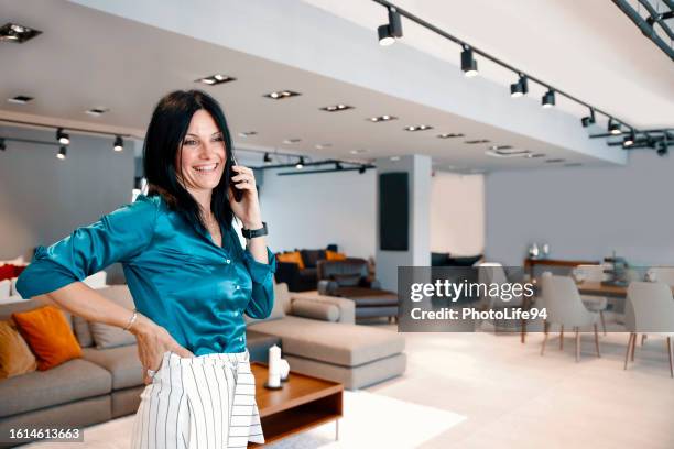 stylish pretty female manager using phone at furniture store - stoffeerder stockfoto's en -beelden