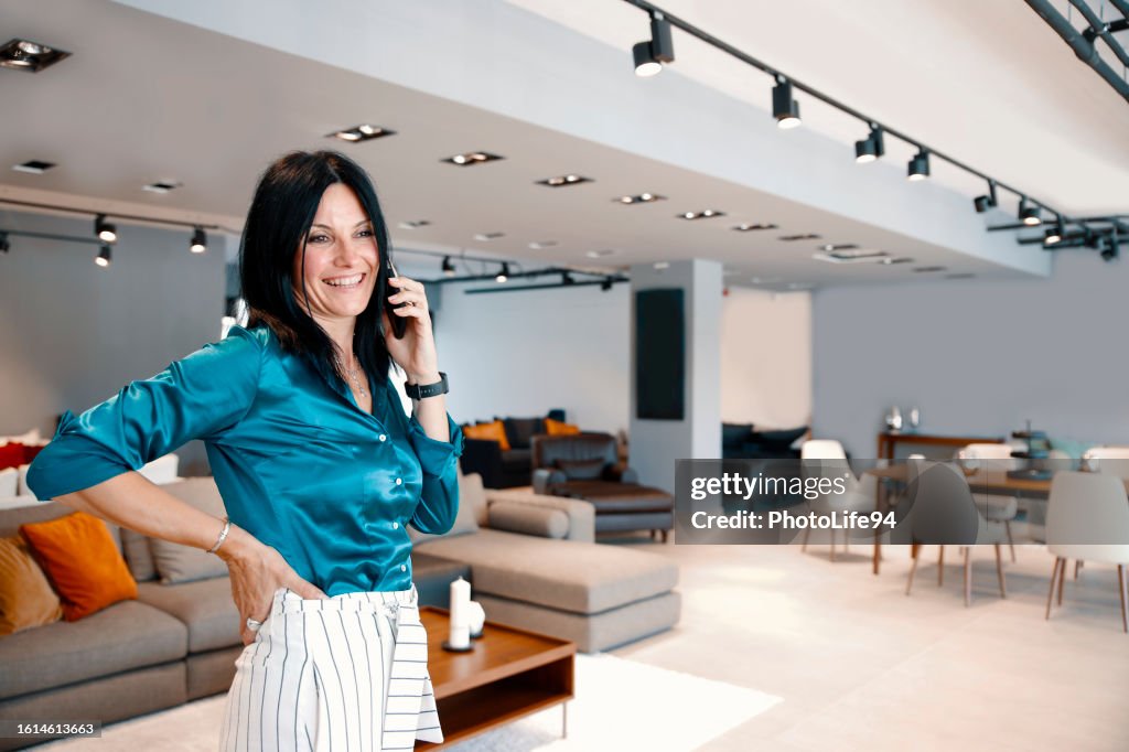 Stylish pretty Female manager using phone at furniture store