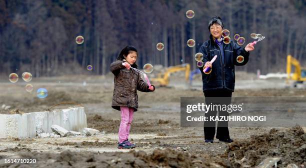 Hiroko Oyama and her granddaughter play with bubbles as they pray for victims of the 74 elementary school children at the Okawa elementary school as...