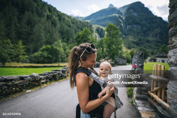 mother carries infant down country road - baby carrier stock pictures, royalty-free photos & images