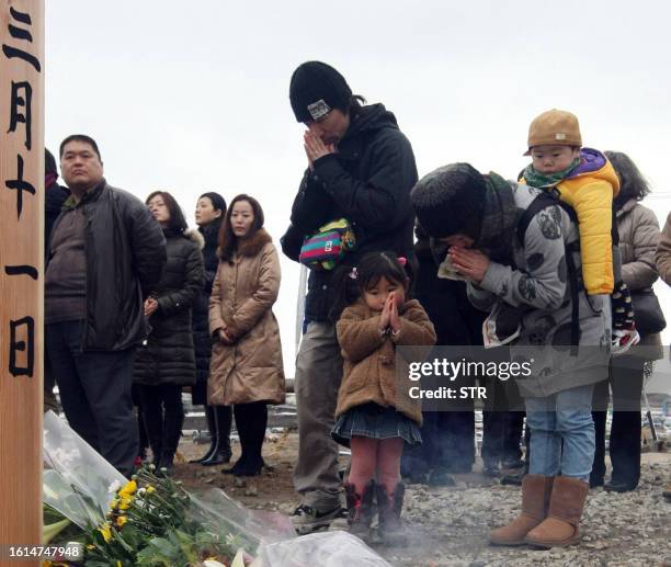 Family lays a flower bouquet on the ground and offer prayers for the victims of the earthquake and tsunami at Natori city in Miyagi prefecture on...