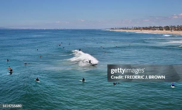 Surfers catch a wave a day after Tropical Storm Hilary swept through the area with large waves hitting south-facing beaches in Huntington Beach,...