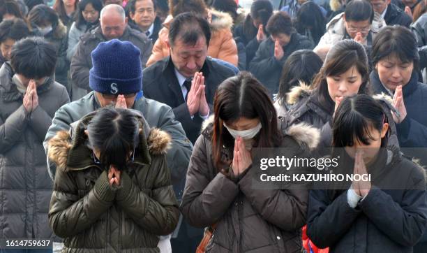 People offer a silent prayer for victims in front of a memorial at the Okawa elementary school as part of the March 11 disaster first year...