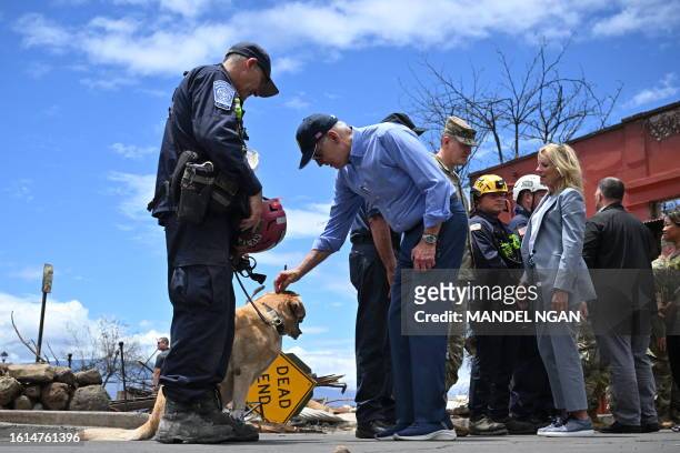 President Joe Biden greets a rescue dog wearing protective boots as he meets with first responders during an operational briefing on response and...