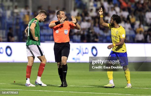 Referee, Mohammed Al Hoaish, talks to Abdulmajeed Al-Sulaiheem of Al-Nassr and Jordan Henderson of Al-Ettifaq during the Saudi Pro League match...