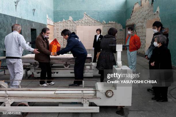 Japan-disaster-tsunami-crematorium FOCUS by John Saeki In a picture taken on March 25, 2011 relatives look on as father Yoshinori Kashiwagi of...