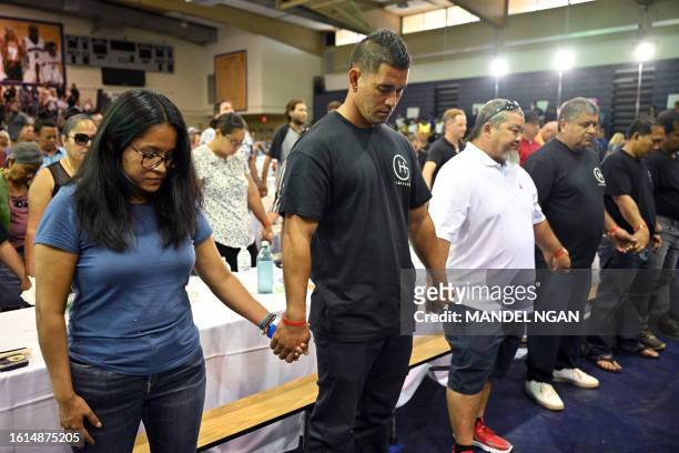 People lower their heads in prayer as US President Joe Biden and First Lady Jill Biden attend a community engagement event at the Lahaina Civic...