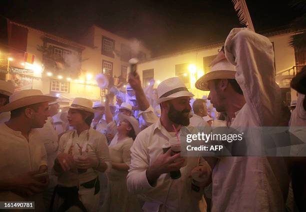 People share a drink as others throw talcum powder at one another as they take part in the carnival of "Los Indianos" in Santa Cruz de la Palma, on...