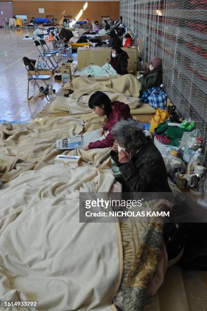 People rest in a gymnasium used as a shelter for displaced persons in the tsunami-devastated town of Otsuchi on March 18, 2011. Japan battled a...