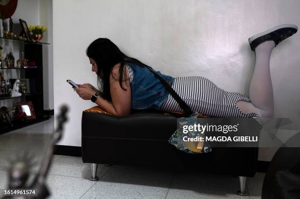 Maria Sanchez checks her mobile phone while resting face down on a sofa, as she is unable to sit down properly after her second biopolymer extraction...