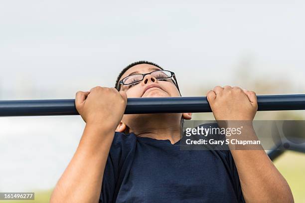 ten year old hispanic boy doing chin ups - boys in pullups stockfoto's en -beelden