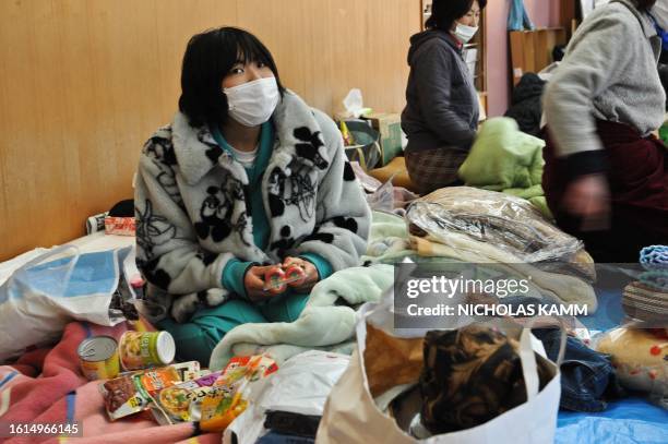 People rest in a gymnasium used as a shelter for displaced persons in the tsunami-devastated town of Otsuchi on March 18, 2011. Japan battled a...