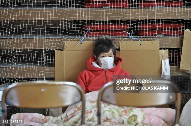 Woman rests in a gymnasium used as a shelter for displaced persons in the tsunami-devastated town of Otsuchi on March 18, 2011. Japan battled a...