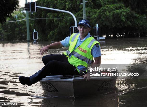 Policeman uses a boat to patrol flooded suburbs for looters as flood waters inundate Brisbane on January 12, 2011. Australia's third-biggest city is...