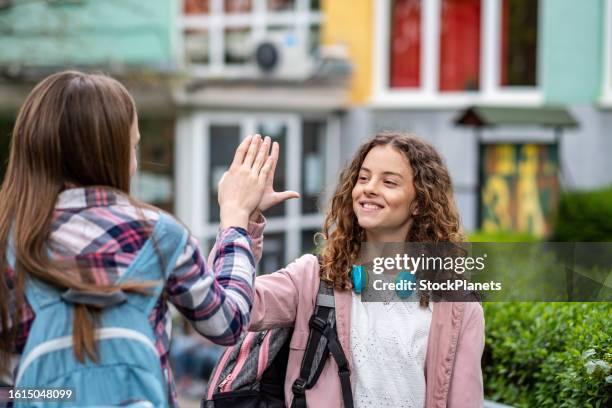 teenage girls greet each other in front of the school - apologize imagens e fotografias de stock