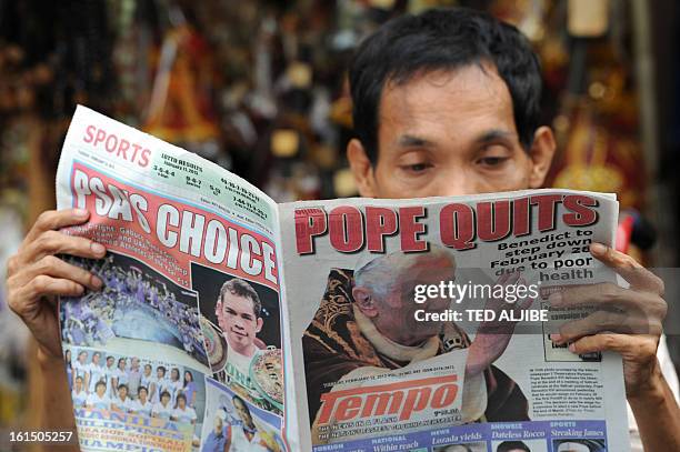 Vendor reads a newspaper featuring the story of the resignation of Pope Benedict XVI near a church in Manila on February 12, 2013. People across the...