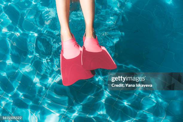 a conceptual image of summer holiday season. a person swimming in a pool, wearing bright pink barbiecore snorkeling fins - barbie stock-fotos und bilder