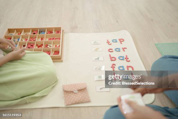 une fille du primaire apprend des mots à l’aide de l’alphabet mobile - spelling stock photos et images de collection