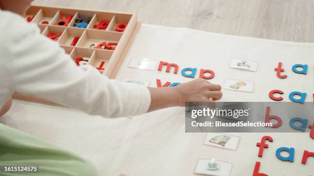 elementary girl learning words using moveable alphabet - english language stock pictures, royalty-free photos & images