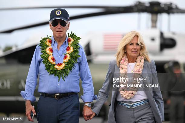President Joe Biden and US First Lady Jill Biden wear Hawaiian leis as they walk to board Air Force One before departing Kahului Airport in Kahului,...
