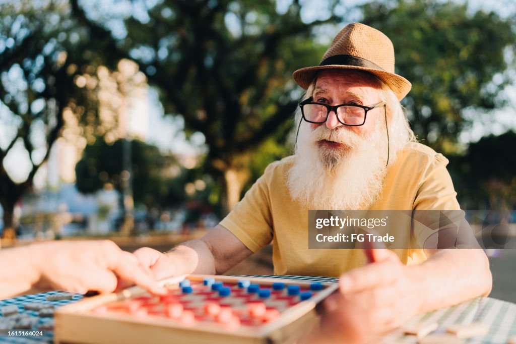 Senior man playing checkers with a friend in the park