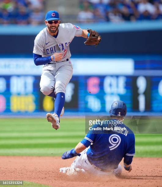 Dansby Swanson of the Chicago Cubs turns a double play over Danny Jansen of the Toronto Blue Jays during the sixth inning in their MLB game at the...