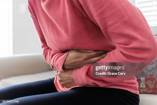 woman holds her abdomen in pain - brechreiz stock-fotos und bilder