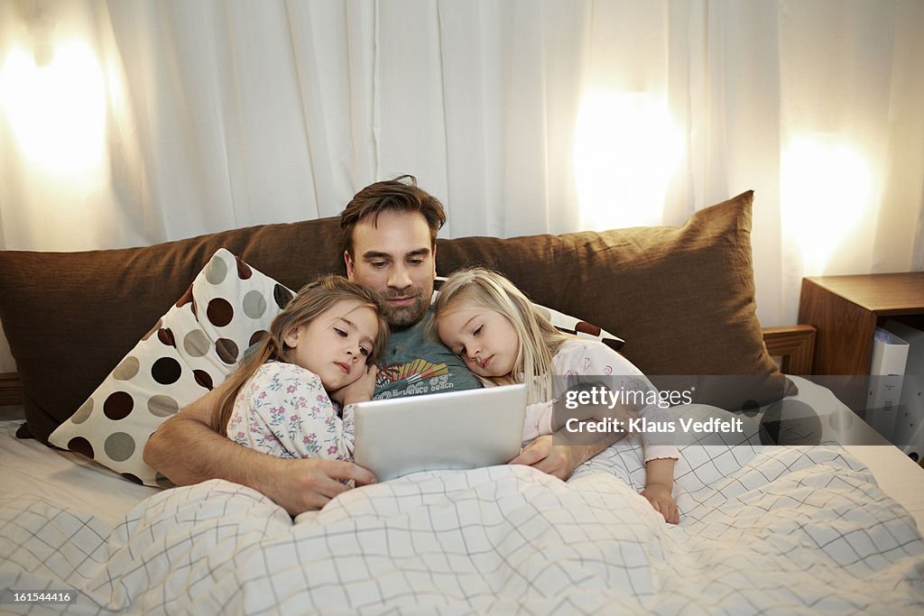 Father & 2 girls reading bedtime story on tablet
