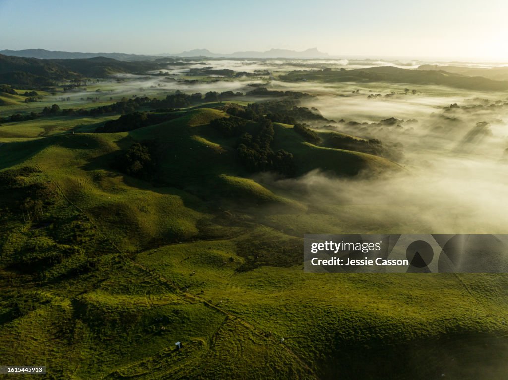 Drone shot of remote hills, misty, blue sky
