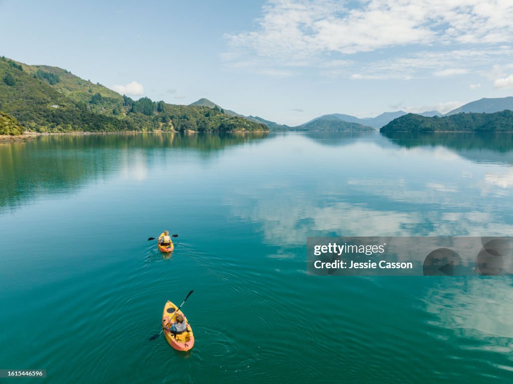 Drone shot of two people canoeing on remote lake with hill surrounds