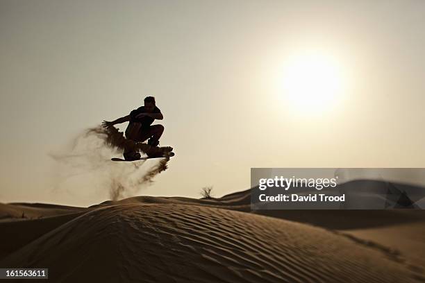 man sand boarding in desert - sand boarding stock pictures, royalty-free photos & images