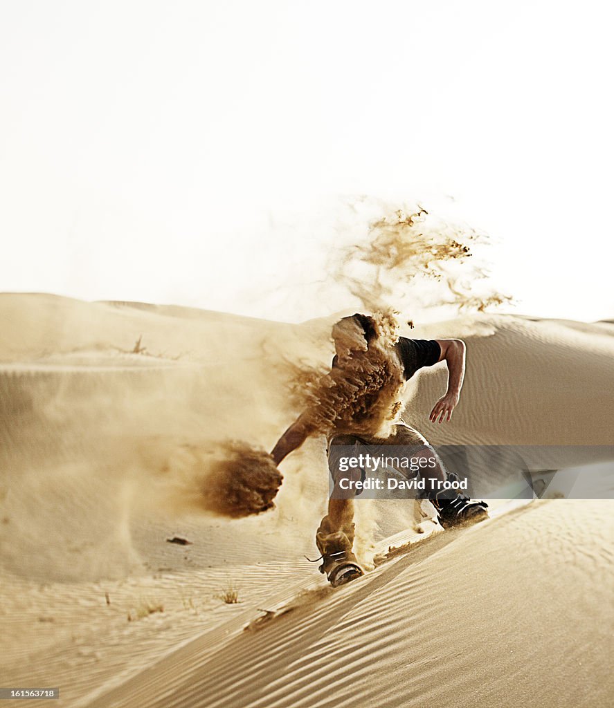 Man sand boarding in desert