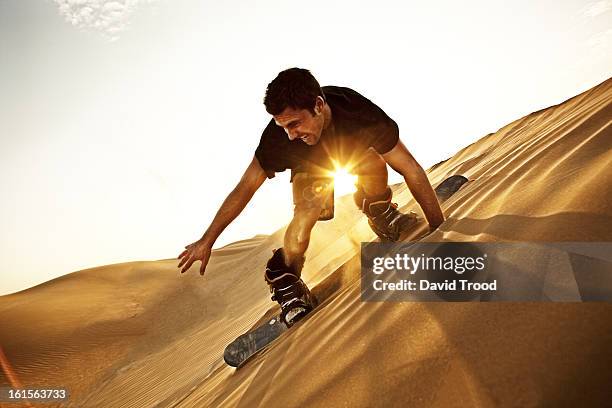 man sand boarding in desert - sand boarding stock pictures, royalty-free photos & images